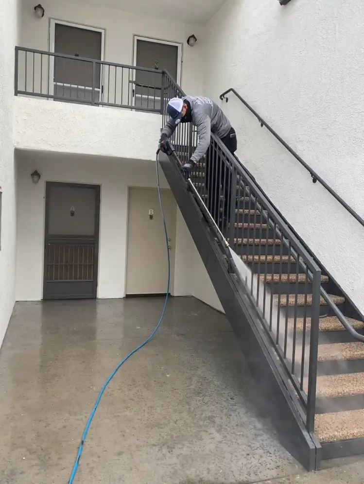 A man on stairs with a hose attached to the railing.