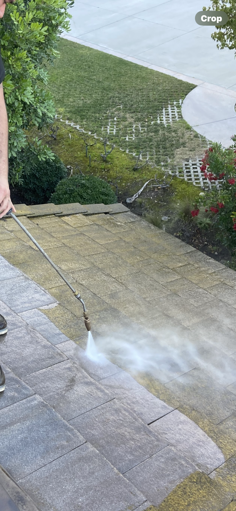 A person using a power washer to clean the patio.