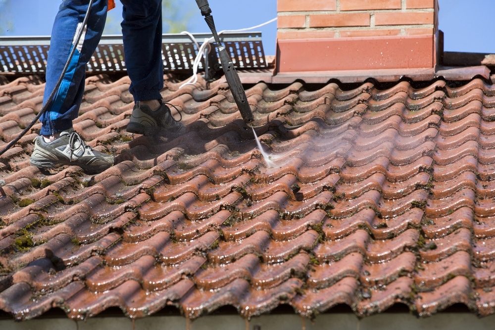 Cleaning tile roof with pressure washer.