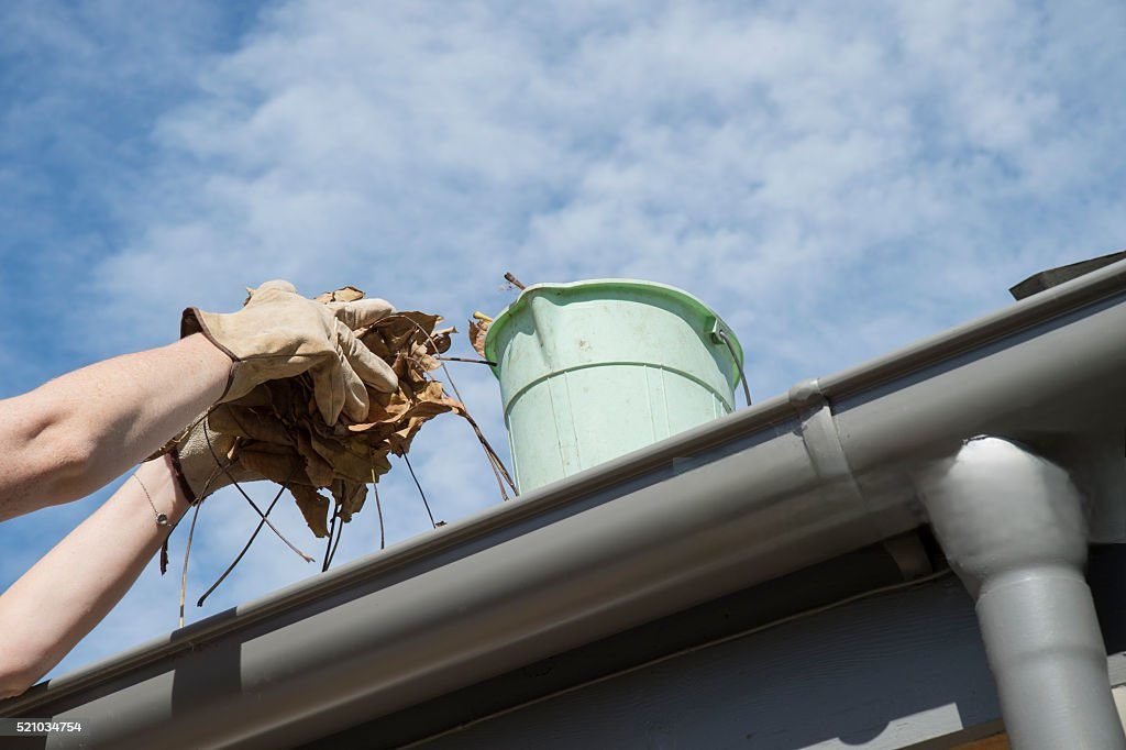 Cleaning leaves from a gutter.