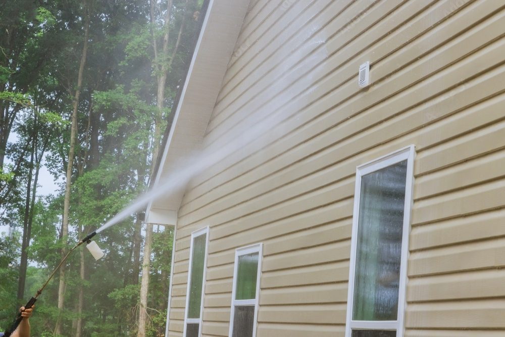 Power washing beige vinyl siding.