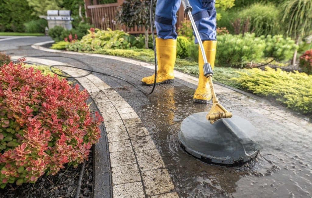 Person pressure washing a patio.