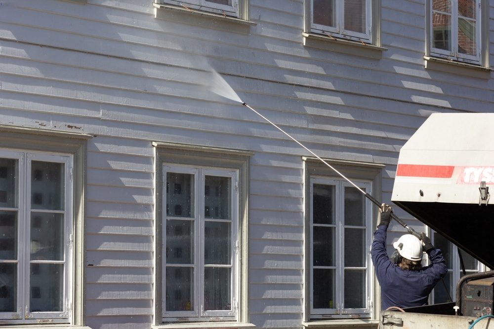 A man pressure washing a building.