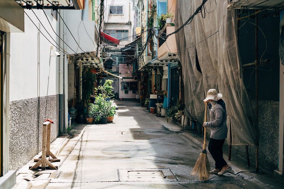 A woman sweeping a narrow alleyway.