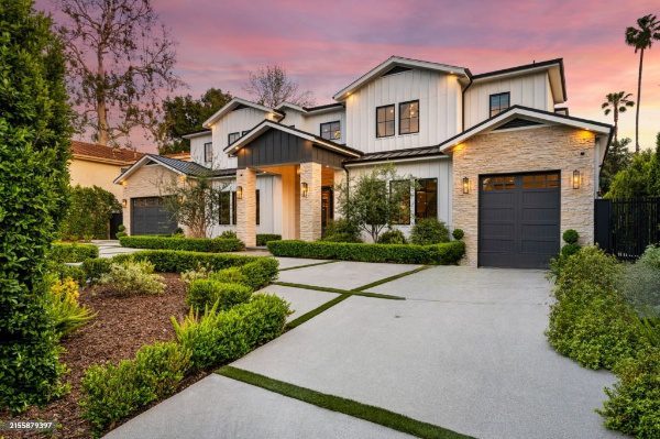 White farmhouse with landscaping and driveway.