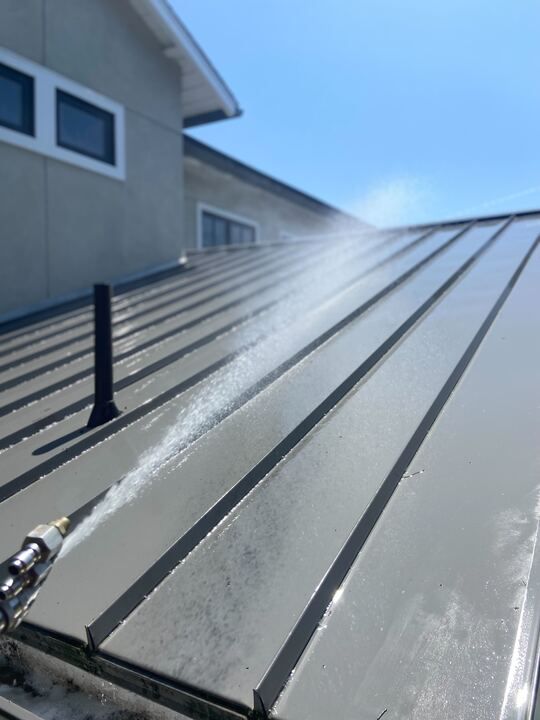 Metal roof being power washed.