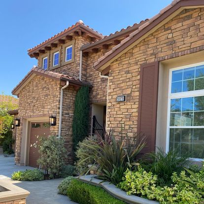 Stone house with a garage door and landscaping.