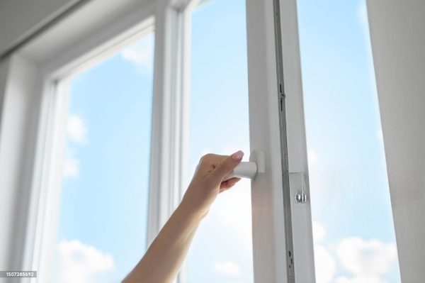 Hand opening white window with blue sky.