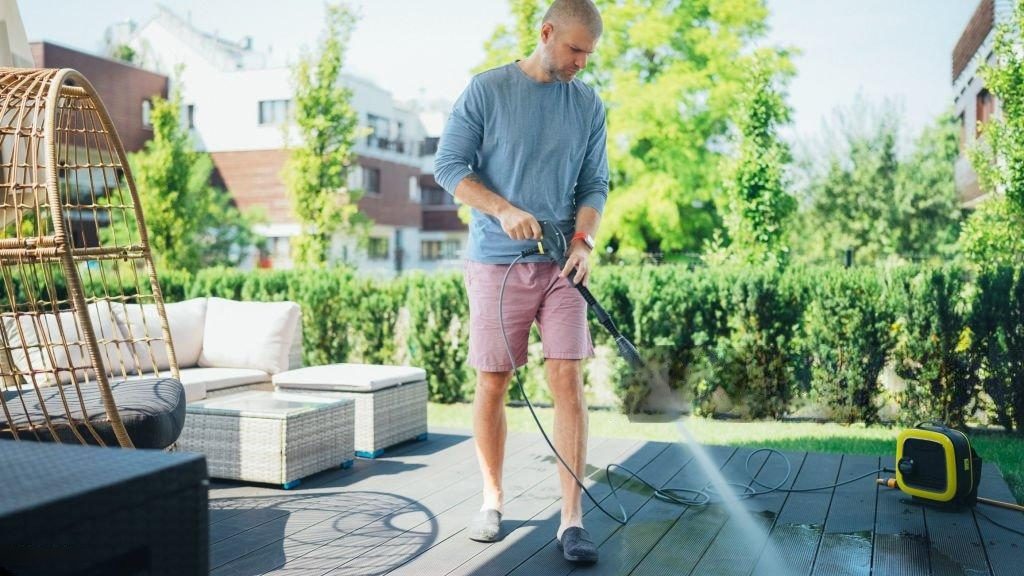 Man cleaning patio with pressure washer.