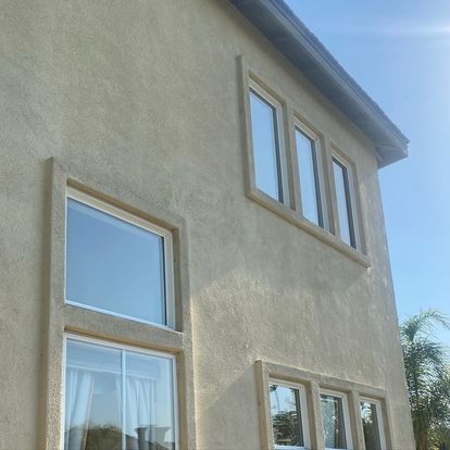 Tan stucco house with windows.