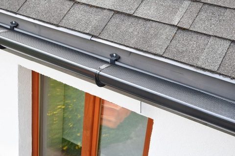 Gray gutter with leaf guard on house.