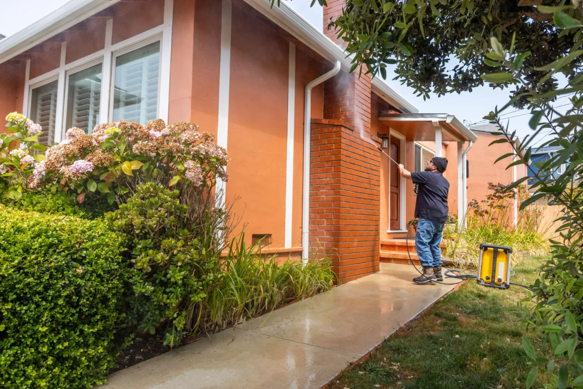 Man cleaning gutters on a house using a ladder.