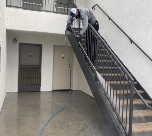 A man on stairs with a hose attached to the railing.