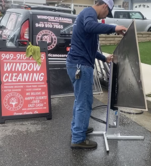 A man is cleaning the window of a car.